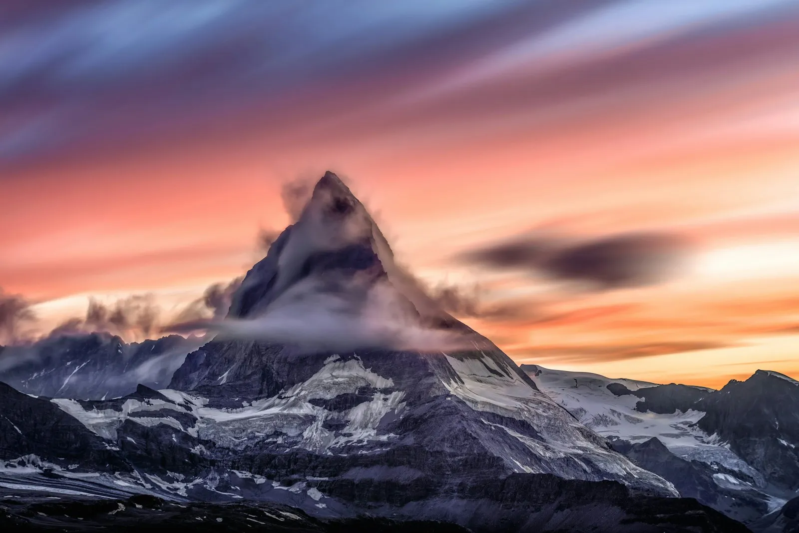 A snow-covered mountain rising through soft clouds