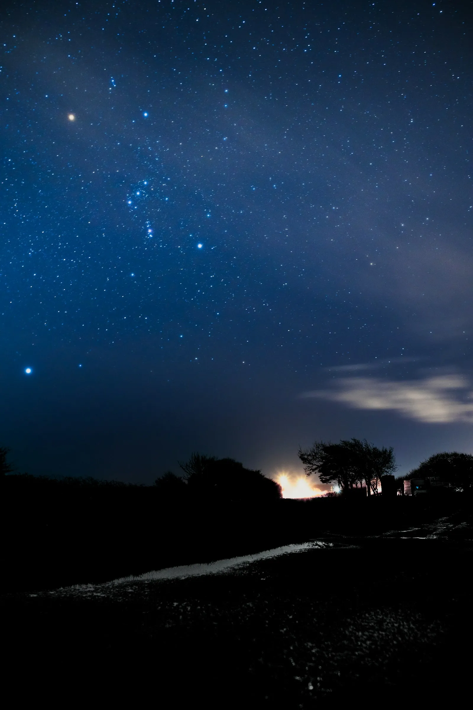 A star-filled night sky above a dark landscape