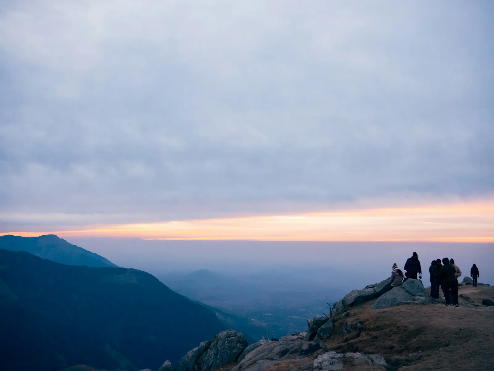 People watching a blue sunrise over mountain ridges