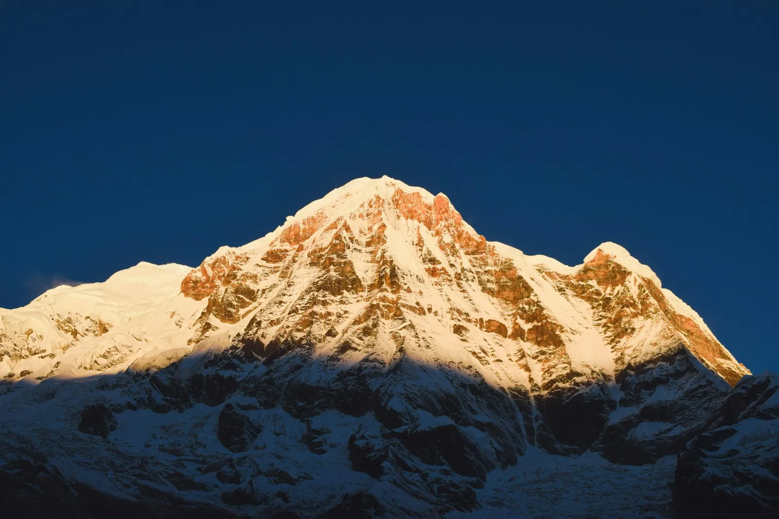 A snow-covered Himalayan peak beneath a clear blue sky