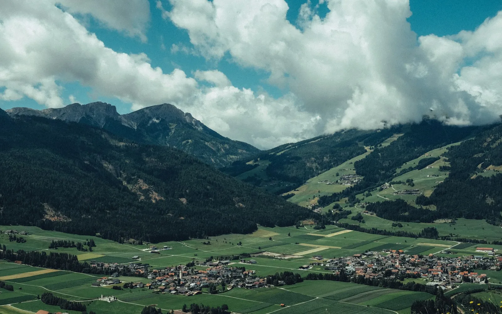 A green valley and village beneath broad mountain slopes